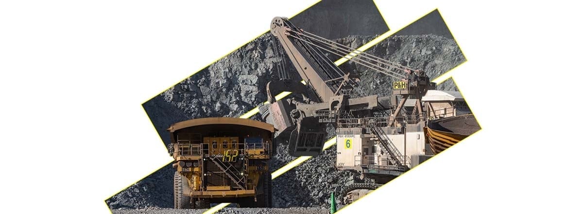 A mining truck and an excavator stand on rocky terrain in an open pit.