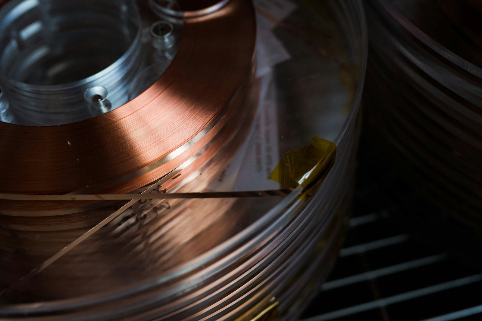 A spool of copper-coloured superconducting tape rests against a dark background.