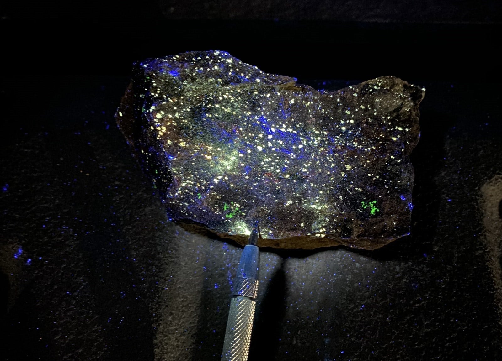 A selected rock sample fluoresces yellow under ultraviolet light.