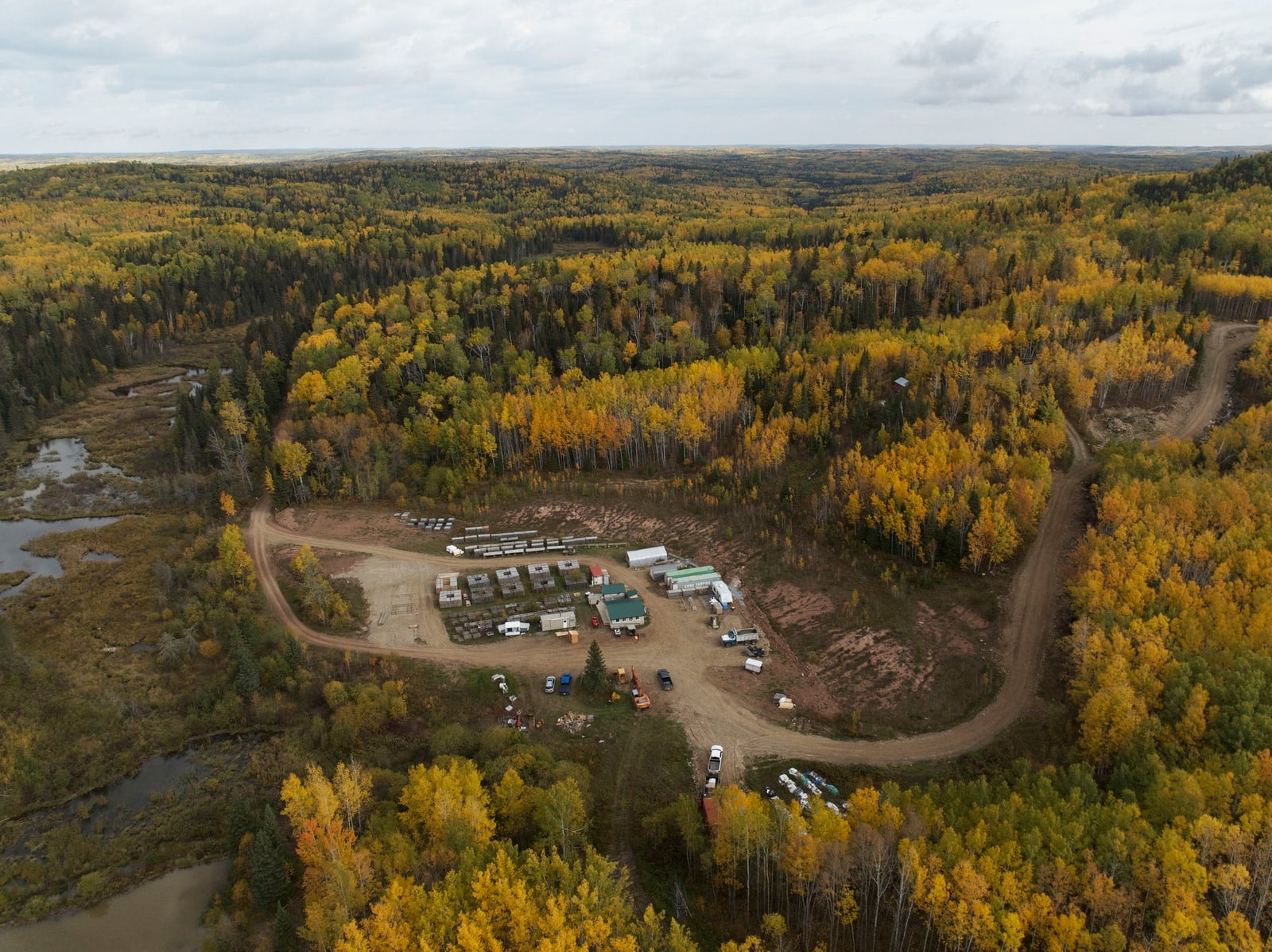 An aerial photograph shows a winding road through a forest with autumn foliage.