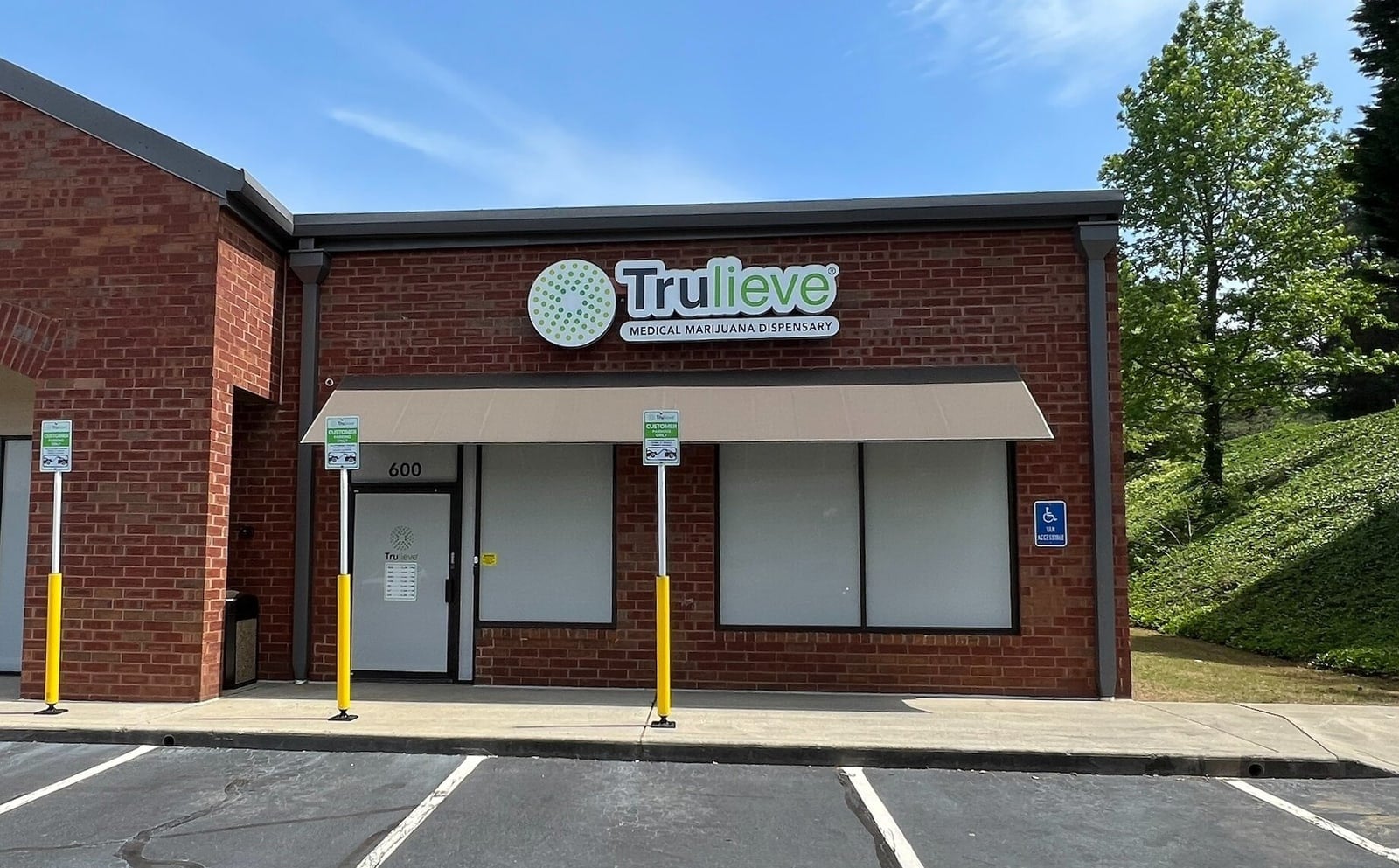 A Trulieve medical marijuana dispensary occupies a single storey brick storefront with the company's sign above a beige awning and an empty parking lot in front.