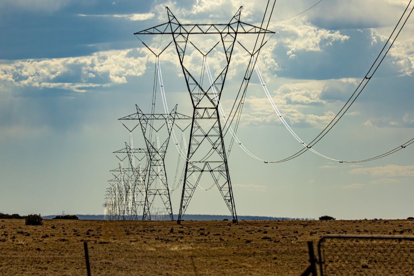 Transmission lines cross an open agricultural field.