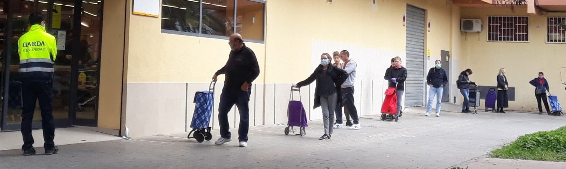 people practicing social distancing outside a clinic in Spain