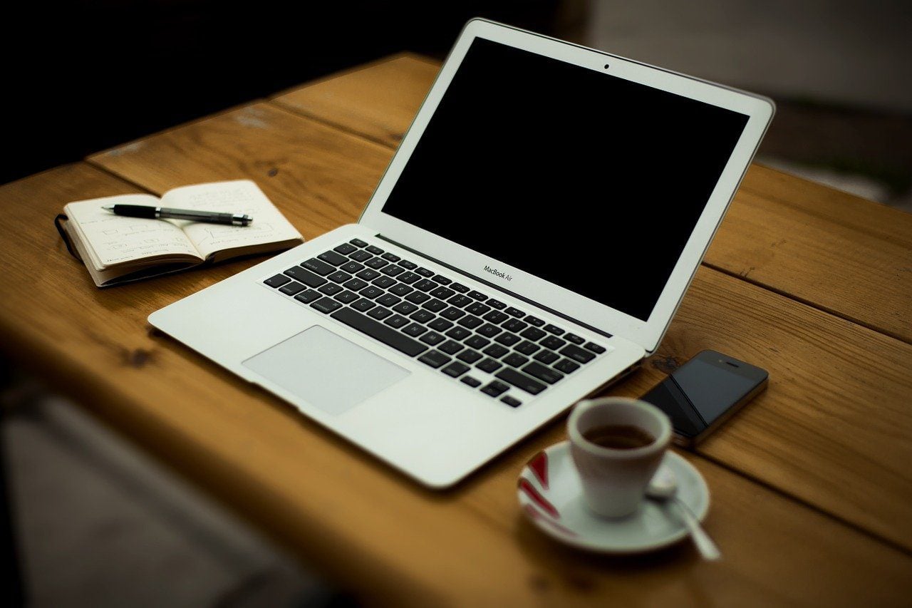 Home office set up with laptop, coffee, cellphone and notepad