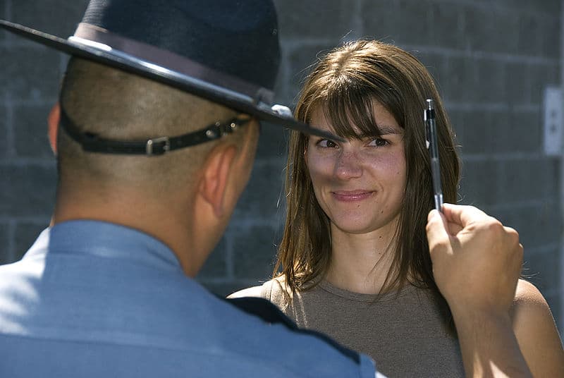 Police officer holding pen near a volunteer's face in a field sobriety test