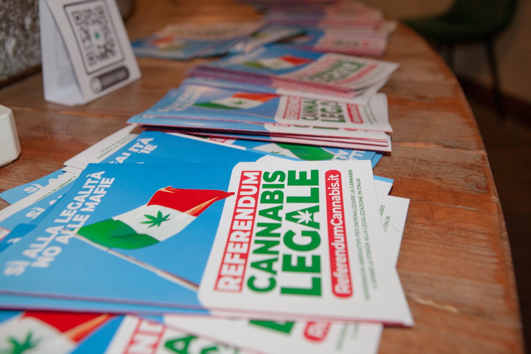A pile of cannabis referendum pamphlets spread out on a wooden table