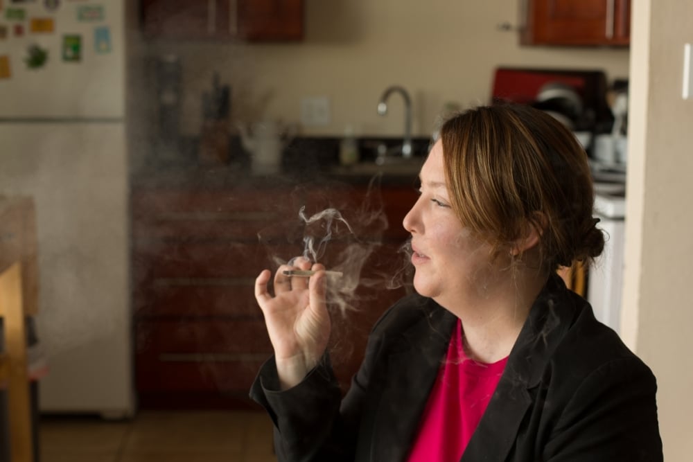 Woman smoking a joint in a kitchen