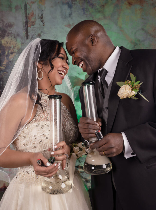 Couple in wedding outfits and holding matching bongs